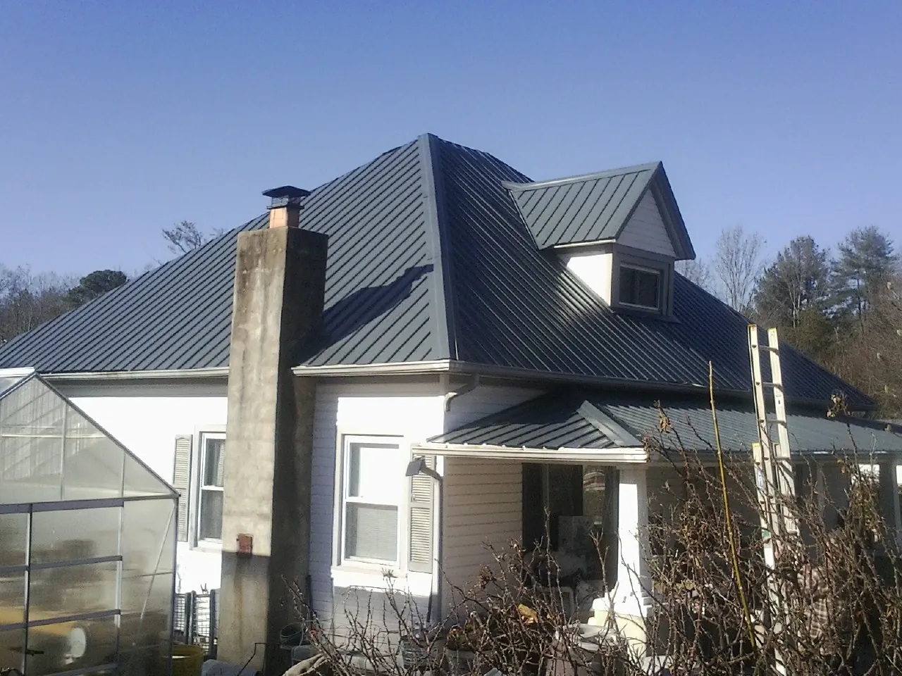 Dark blue standing seam metal roof on a white farmhouse with dormer — Slate & Tile Roof Repair by Roofing Brothers in Bear Mountain