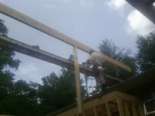 Carpenter setting a ridge beam over a new addition frame — Ice Dam Removal by Roofing Brothers in Bear Mountain