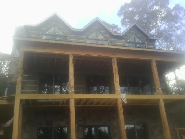 Dormers and porch framing on a large log home under construction — Roof Coating work by our crew in Bear Mountain