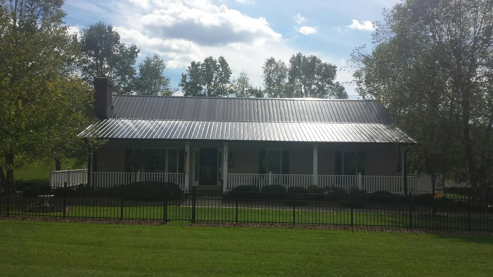 Gray metal roof on a brick ranch with a full width front porch — Gutter Guard Installation work by our crew in Bear Mountain