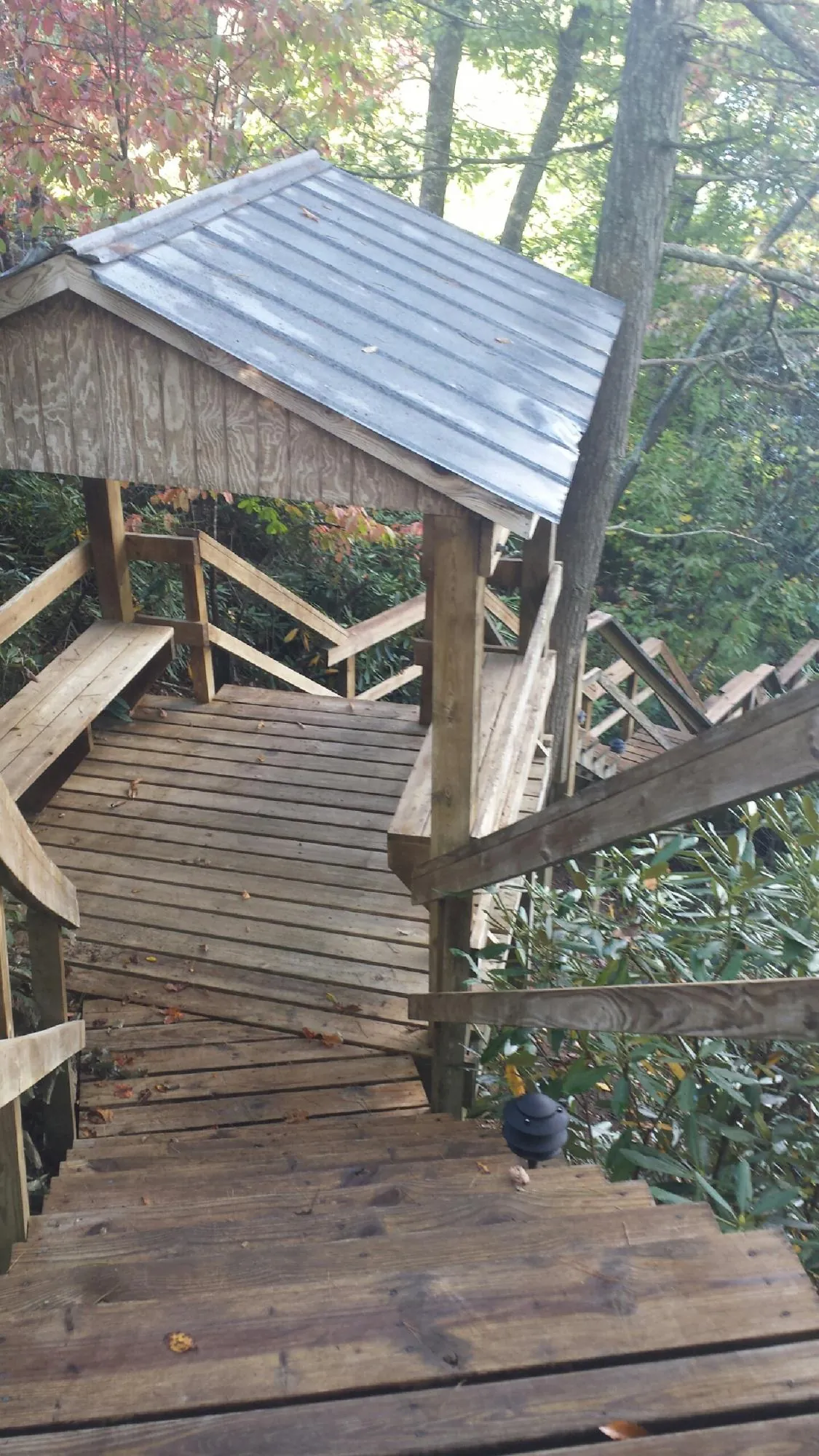 Metal roofed shelter over wooden steps on a wooded walkway — Skylight Repair & Installation work by our crew in Bear Mountain