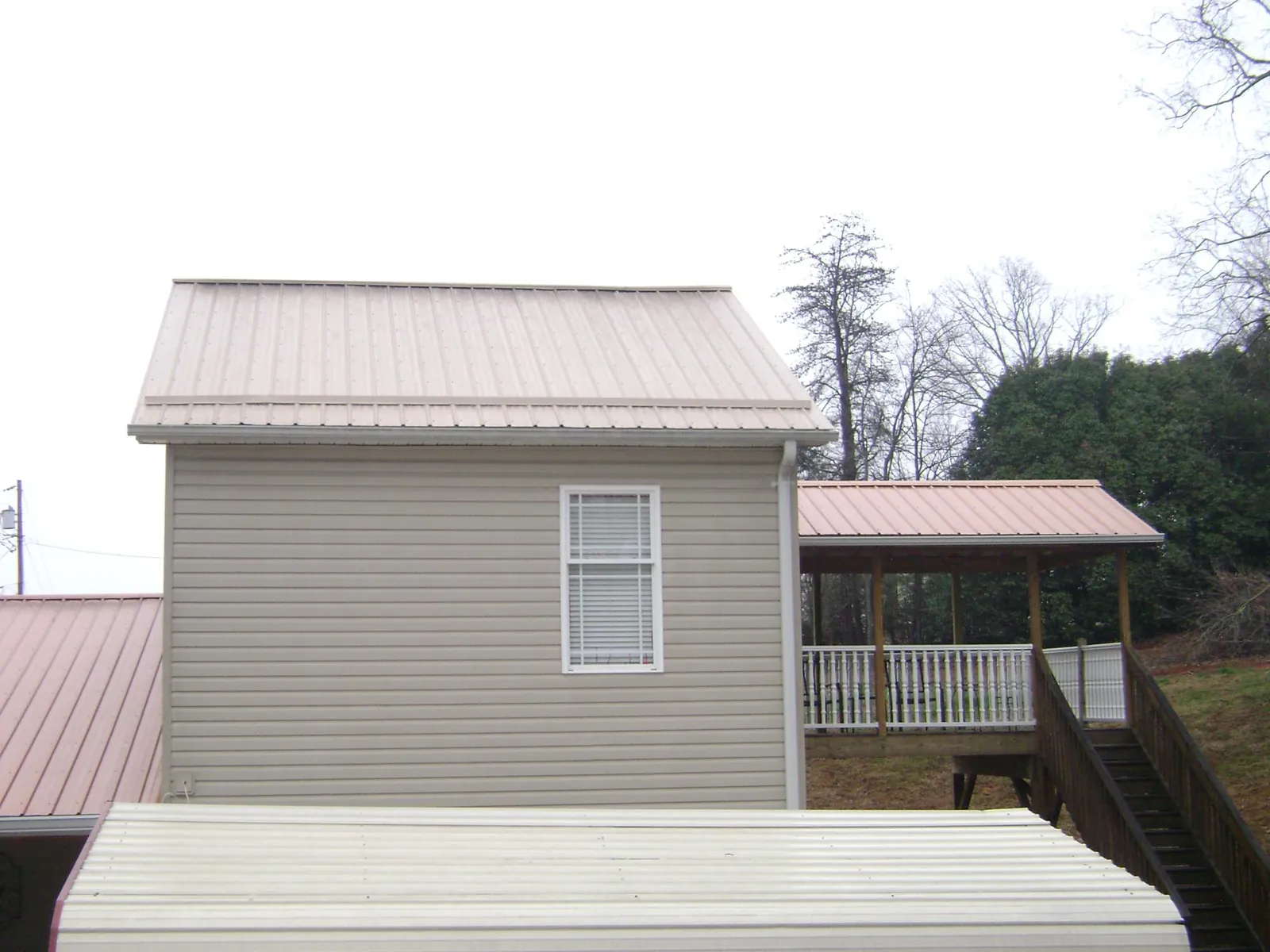 Tan metal roofs on a two story addition and attached porch, from a Roof Replacement job in Bear Mountain