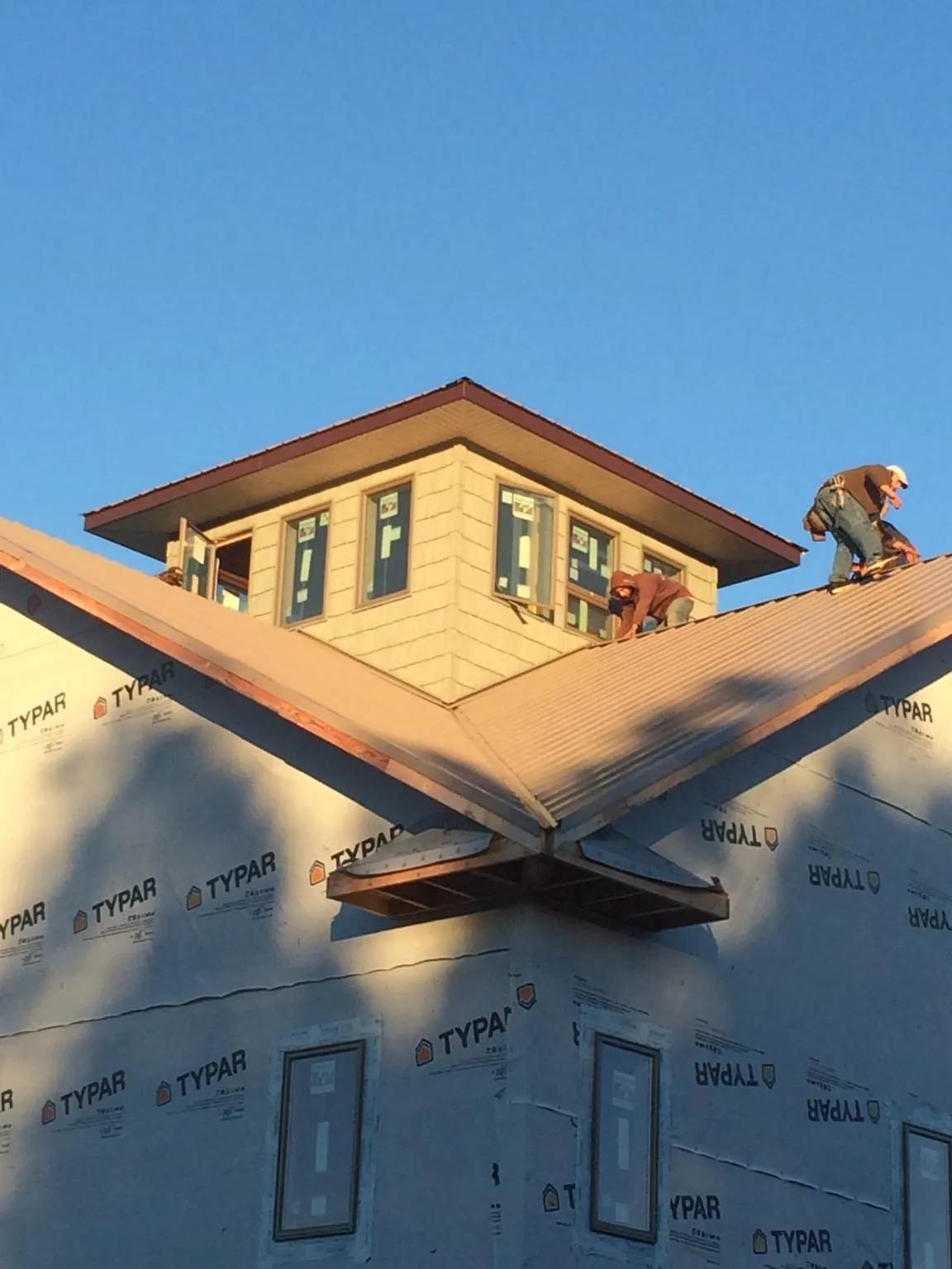 Roofers working around a rooftop cupola on a new metal roof at sunset — Roof Waterproofing in Bear Mountain by Roofing Brothers